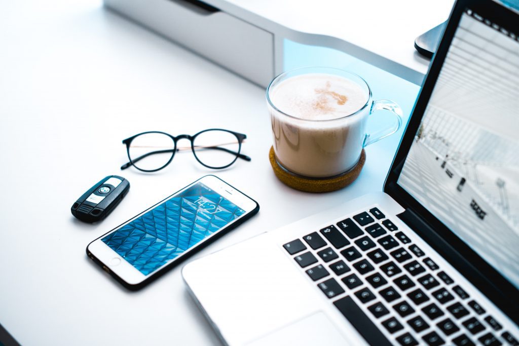 A phone, glasses, a cappuccino, and a laptop