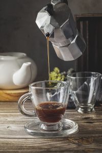 Serving coffee in a glass cup with a moka pot