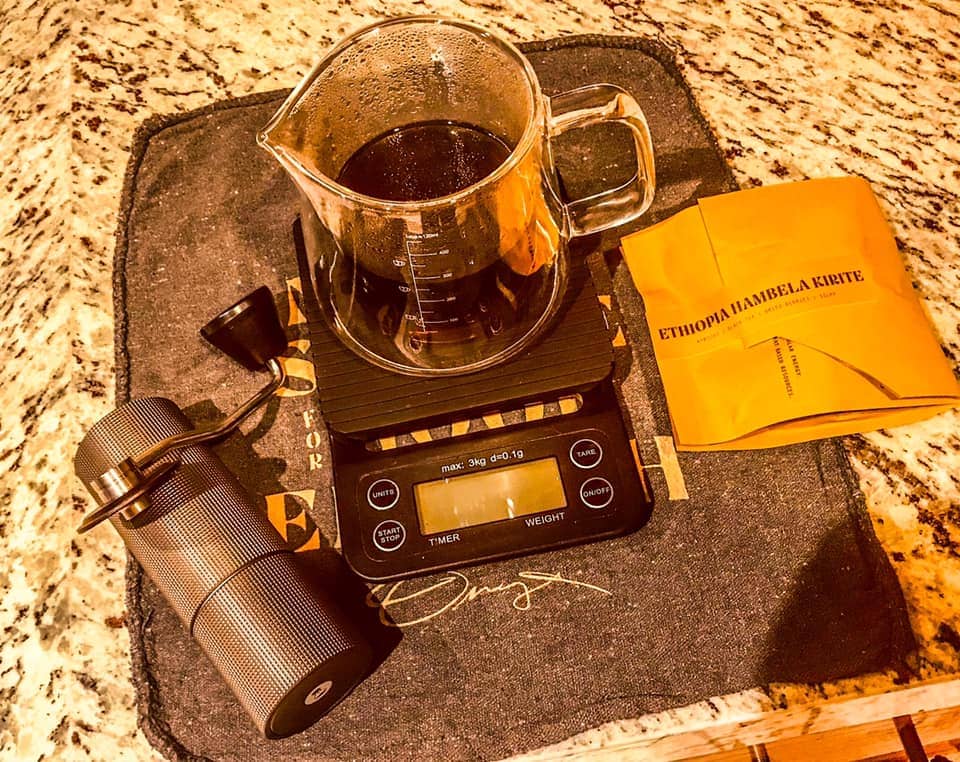 TIMEMORE C2 grinder along with a digital scale, and a bag of specialty coffee.