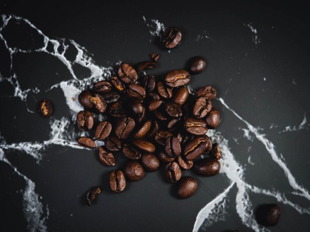 granos de café tostados sobre una superficie negra de mármol