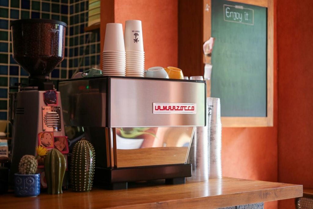 Máquina de espresso al lado de un molino en la barra de una cafetería