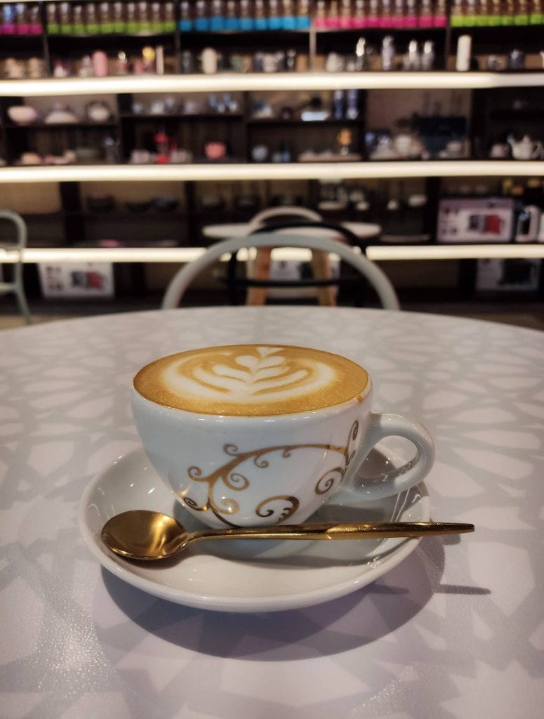 cappuccino servido con latte arte y cucharilla dorada